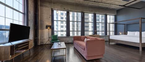Une chambre moderne dotée d’une grande fenêtre, d’un lit, d’un canapé, d’une télévision et d’une table basse.