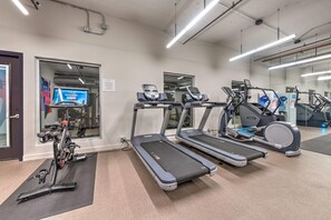 Un gimnasio con cintas de correr, bicicletas estáticas y una máquina de remo.