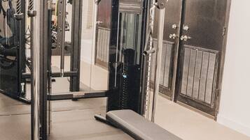 A gym with exercise equipment, a bench, and a door labeled 'HVAC'.