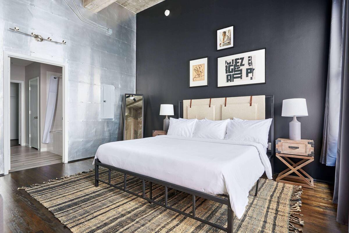 Ein modernes Schlafzimmer mit einem großen Bett, zwei Nachttischen, einem Spiegel und Bildern an der Wand.