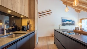 Eine moderne Küche mit Holzausstattung, einer integrierten Kochinsel und einem Skiständer an der Wand.