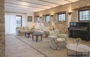 Ein Zimmer mit Klavier, floralen Sofas, einem Couchtisch und einem Kamin.
