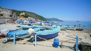 Ein Strand mit Booten, Sonnenschirmen und einer felsigen Klippe.