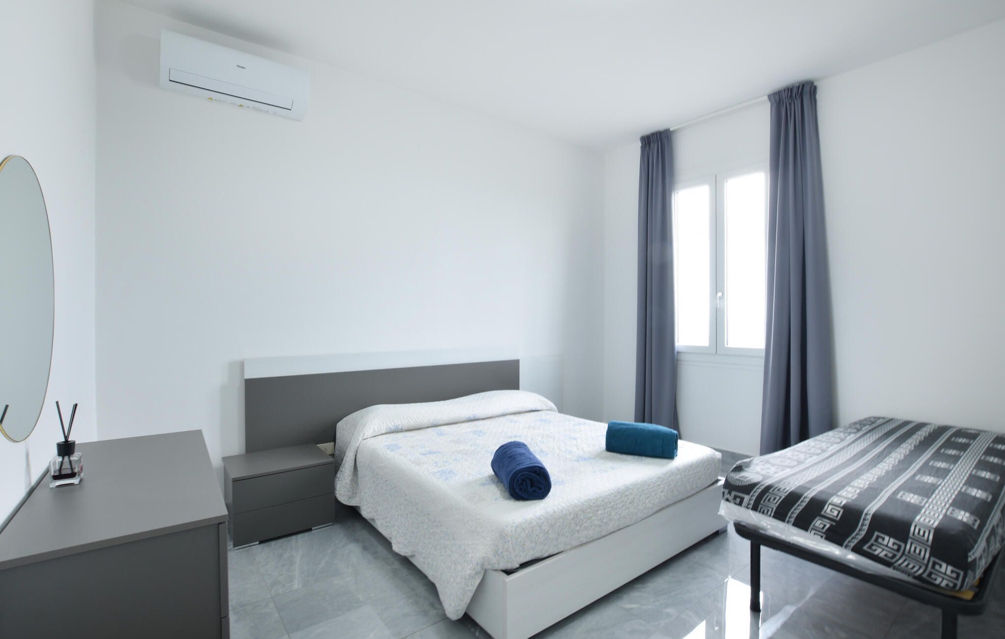 A modern bedroom with a bed, bedside table, and a window with curtains.