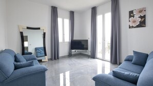 Ein modernes Wohnzimmer mit Flachbildfernseher, zwei Sofas, einem großen Spiegel und einem Gemälde an der Wand.