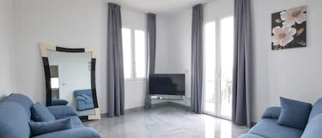 Ein modernes Wohnzimmer mit Flachbildfernseher, zwei Sofas, einem großen Spiegel und einem Gemälde an der Wand.