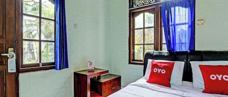 A room with a bed, a nightstand, a window with curtains, and a door with a handle.