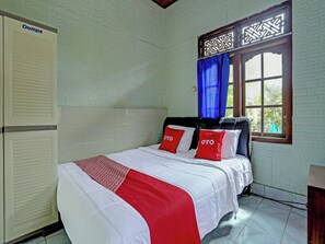 Ein Zimmer mit einem Bett, einem Heizkörper, einem Fenster mit Vorhängen und einer Wand mit Muster.