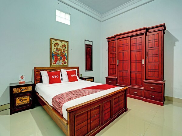 A bedroom with a wooden bed, red pillows, a nightstand, a wardrobe, and a painting on the wall.