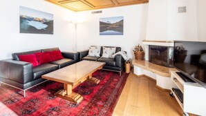 Una sala de estar con techo de madera, chimenea, sofá, mesa de centro y televisor.