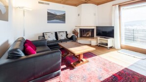 Una sala de estar con chimenea, un sofá, una mesa de centro y un televisor.