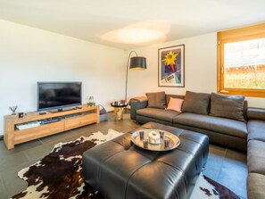 Ein modernes Wohnzimmer mit Flachbildfernseher, Ledersofa, Couchtisch und einem Teppich aus Rindsleder.