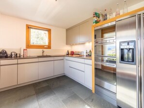 Eine moderne Küche mit weißen Schränken, einem Einbauofen, einem Wasserspender und einem Fenster mit Blick.
