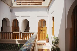 A courtyard with wooden doors, a tiled floor, and a railing. - Riad Mama Square (Marrakech)