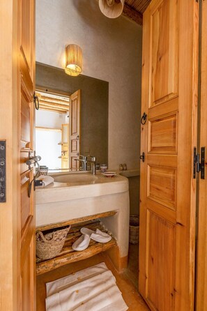 A wooden bathroom with a sink, mirror, and towel rack. - Riad Mama Square (Marrakech)