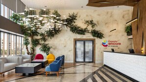 Un vestíbulo moderno con mostrador de recepción, zona de estar y plantas decorativas.