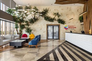 A modern lobby with a reception desk, seating area, and decorative plants. - Ramada Encore by Wyndham Istanbul Arnavutkoy (Istanbul)