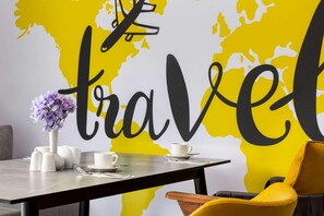 A dining table set with white cups and saucers, a vase with purple flowers, and a chair with a yellow cushion. - Ramada Encore by Wyndham Istanbul Arnavutkoy (Istanbul)
