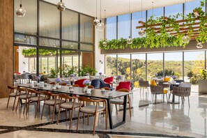 Un comedor amplio con ventanas grandes, muebles modernos y plantas colgantes.