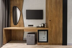 A modern room with a wooden desk, a flat-screen TV, a coffee machine, and a small refrigerator. - Ramada Encore by Wyndham Istanbul Arnavutkoy (Istanbul)