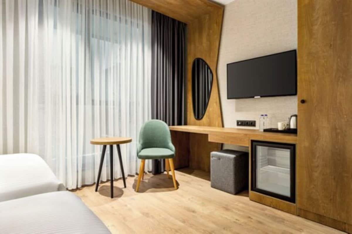 Ein Hotelzimmer mit Bett, Schreibtisch mit Stuhl, Fernseher, Minikühlschrank und einer Kaffeemaschine.