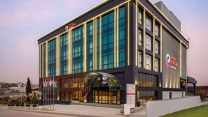 Un hotel moderno con fachada de vidrio, una entrada destacada con techo curvo y un cartel que indica que es un hotel Marriott.