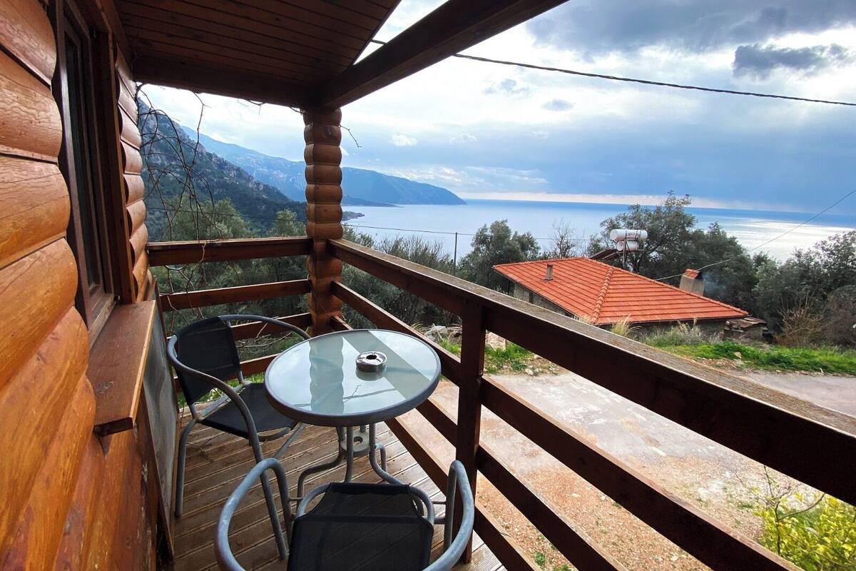 Une cabane en bois dotée d’un balcon donnant sur un lac et des montagnes.