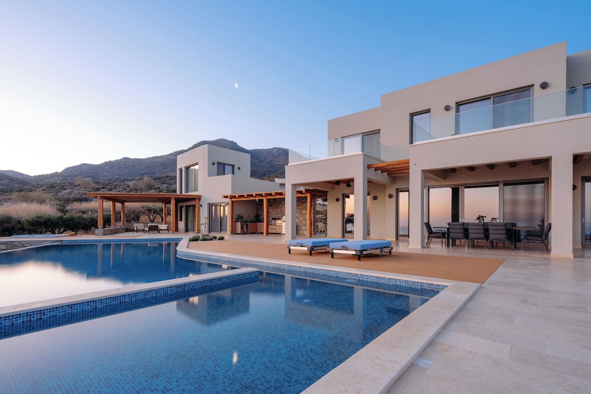 Uma área de piscina moderna, com vista clara da piscina, espreguiçadeiras e um terraço coberto.