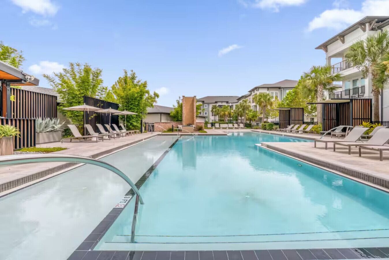 A swimming pool with lounge chairs and a modern building in the background.