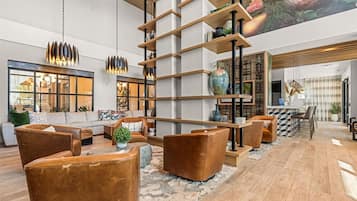 A spacious living area with a high ceiling, a modern staircase, and a dining area with a bar.