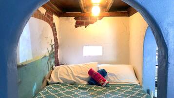 A room with a bed, a window, and a wall with peeling paint.