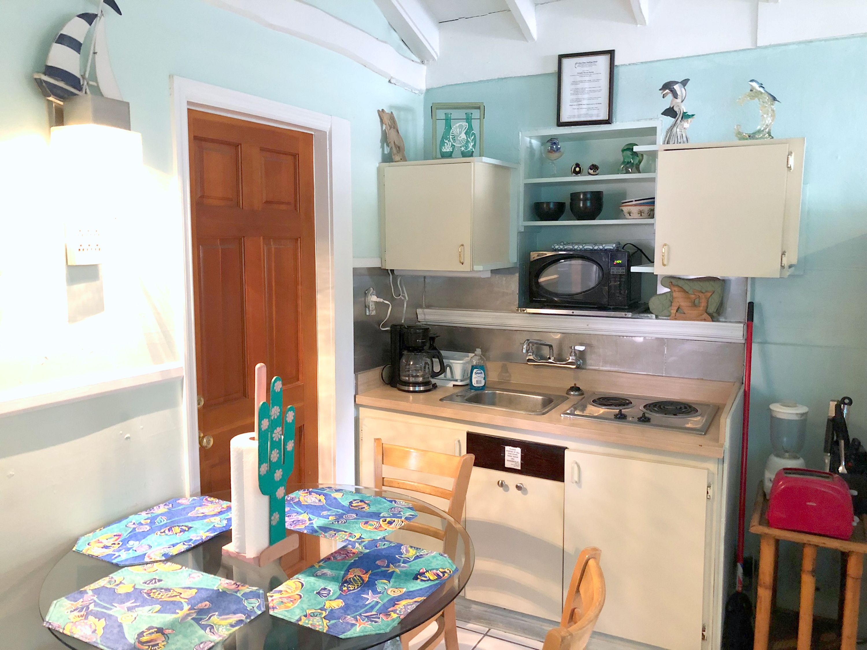 A compact kitchen with a microwave, sink, and a small dining area with a table and chairs.
