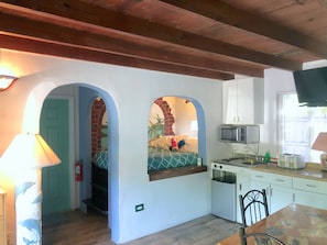 A compact kitchen with a microwave, toaster, and sink. There is a small dining table with chairs.