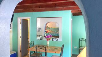 A dining area with a wooden table and chairs, a vase with flowers, and a view through a window.