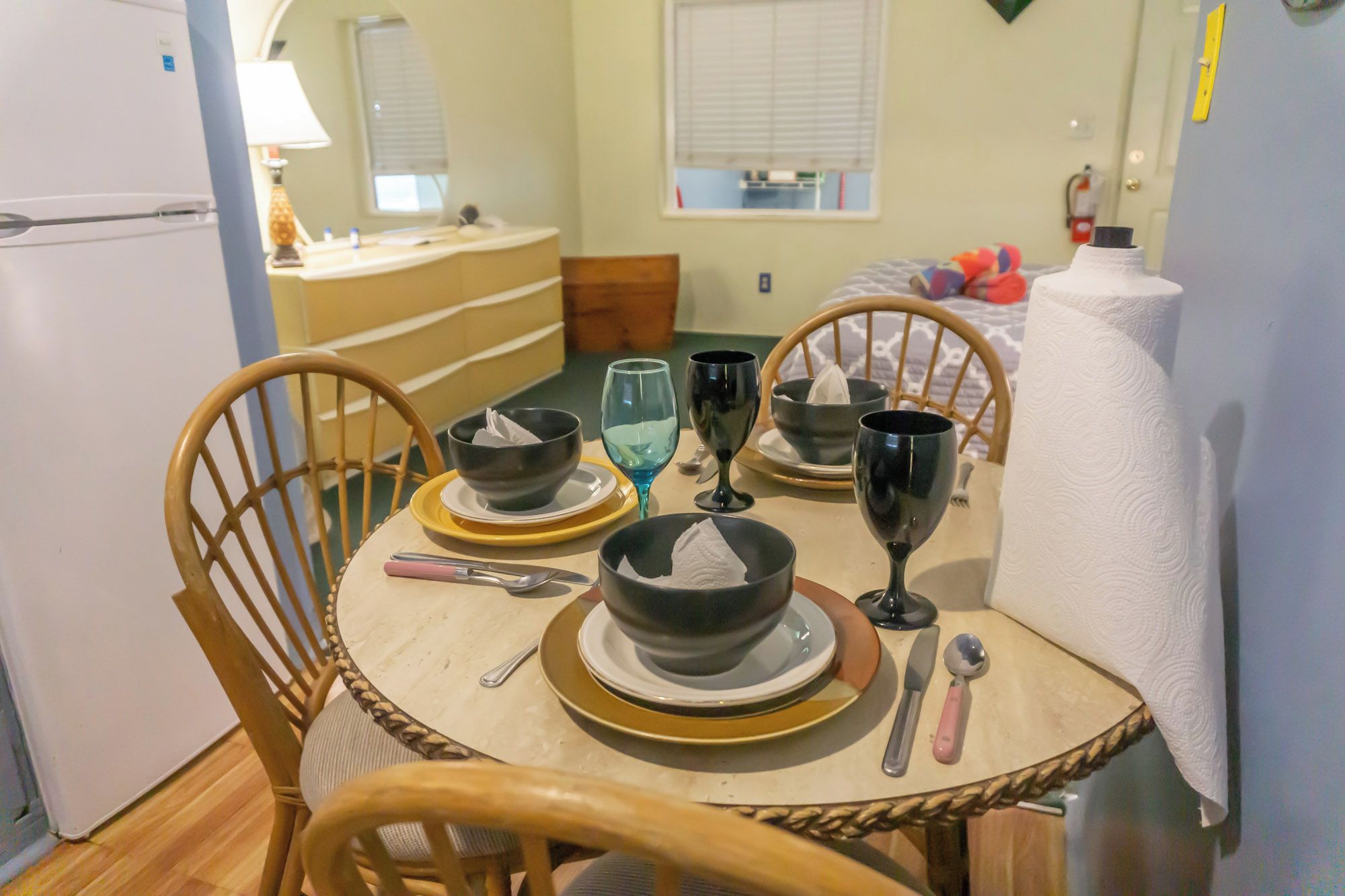 A dining area with a round table set for four, including bowls, wine glasses, and cutlery.