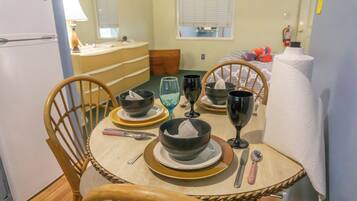 A dining area with a round table set for four, including bowls, wine glasses, and cutlery.