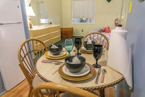 Comedor con una mesa redonda dispuesta para cuatro, con platos, copas de vino y cubiertos.