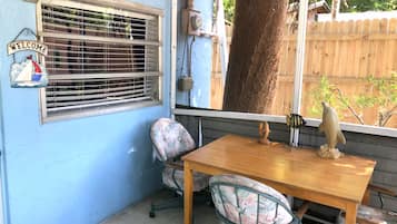 A blue-painted room with a wooden table, two chairs, a 'Welcome' sign, and a window with blinds.