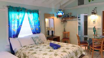 A bedroom with a bed, a chair, a table, and a hanging light fixture.