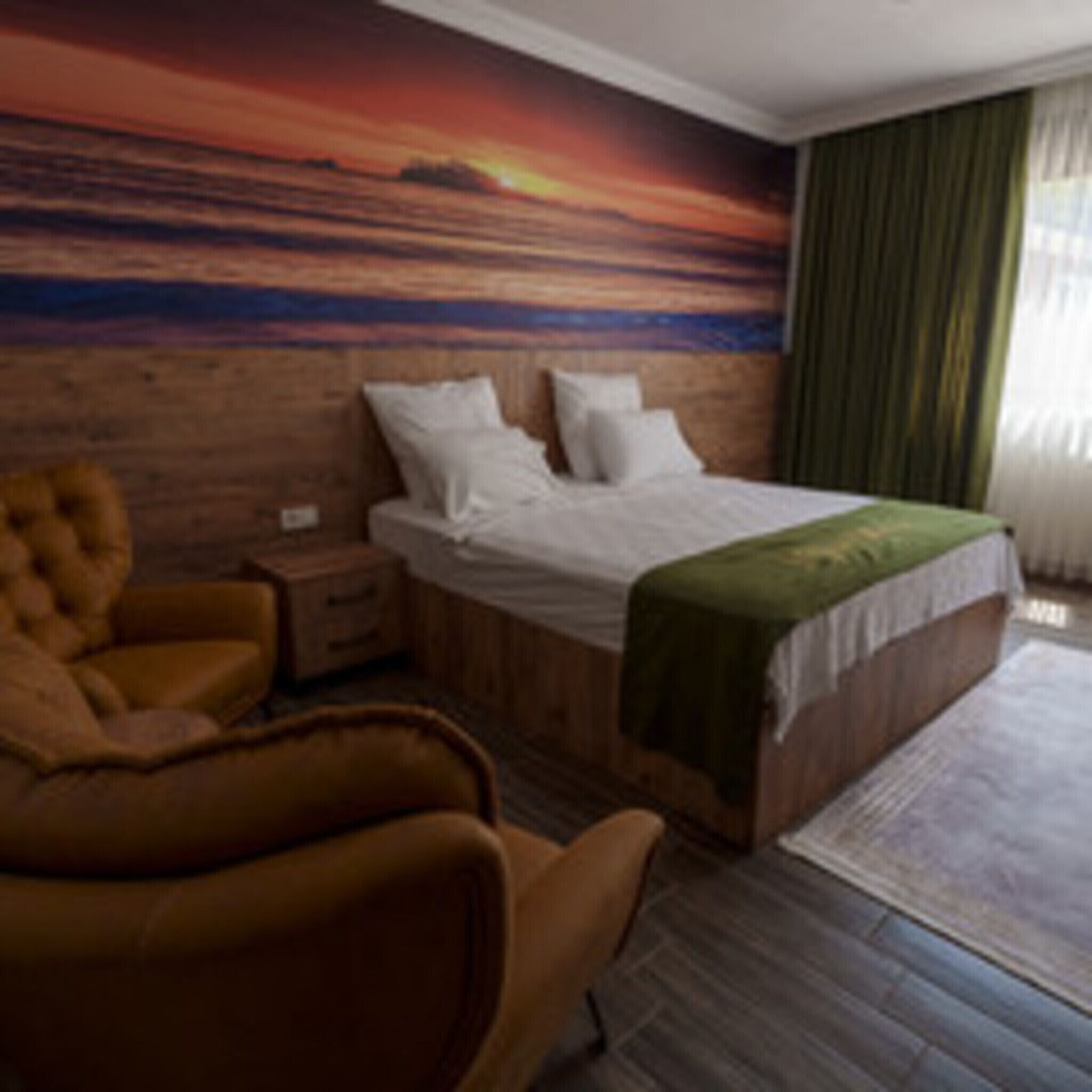 A bedroom with a wooden headboard, a bed with white bedding, a green throw, a brown armchair, and a nightstand.