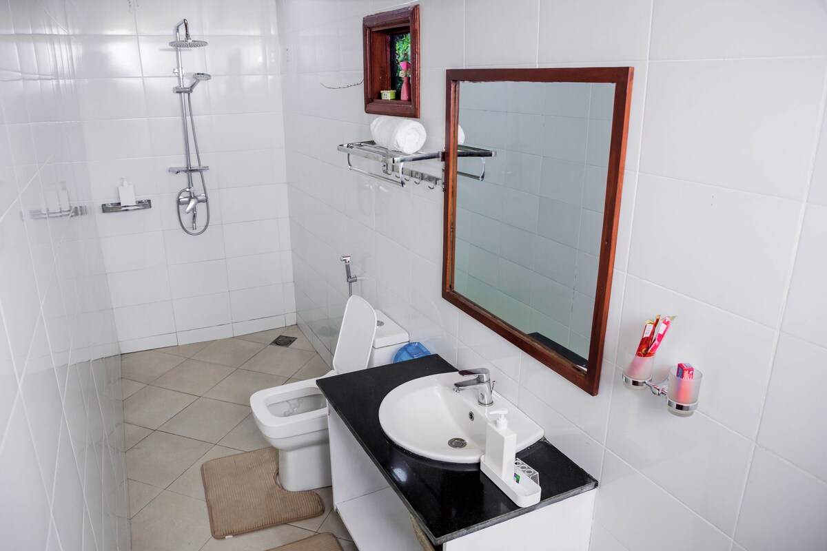 A modern bathroom with a shower, toilet, sink, and mirror.