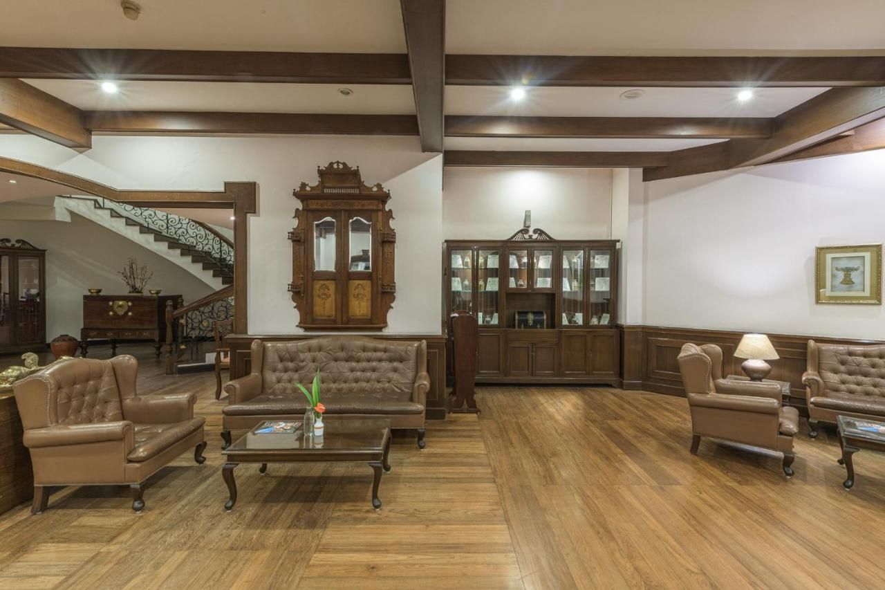 Un salón comedor amplio con una imponente escalera, muebles de madera y un candelabro.