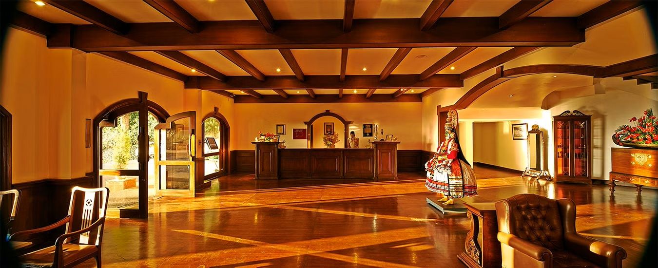 A lobby with wooden flooring, a reception desk, and a statue.