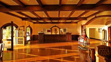 A lobby with wooden flooring, a reception desk, and a statue.