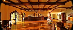 A lobby with wooden flooring, a reception desk, and a statue.