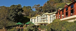 A multi-story hotel with balconies, surrounded by lush greenery and trees.