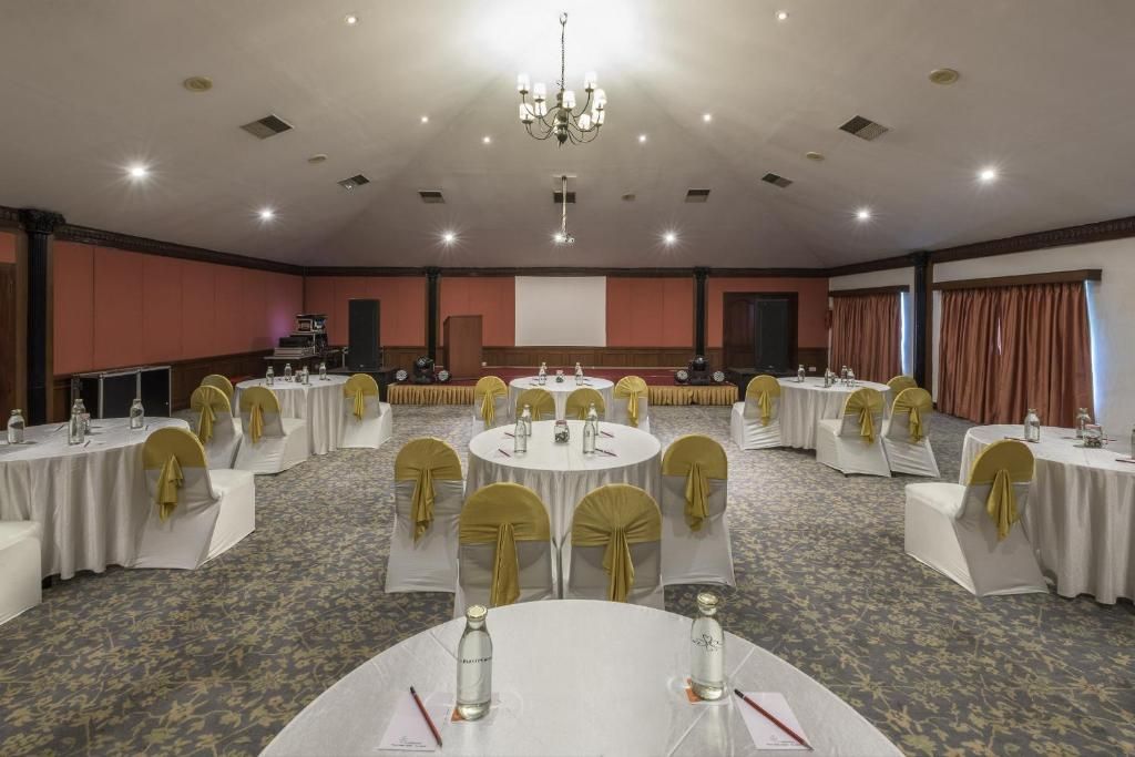 A conference room with round tables, chairs, and a projector screen.