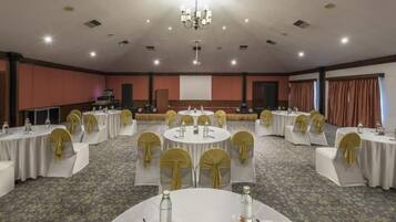 A conference room with round tables, chairs, and a projector screen.