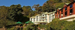 A multi-story hotel with balconies, surrounded by lush greenery and trees. - Club Mahindra Lake View Munnar (Devikolam)
