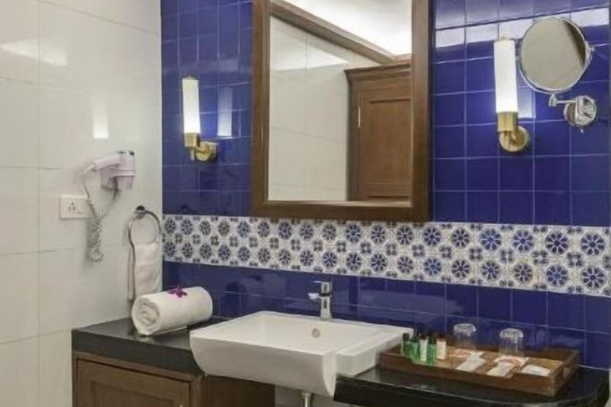 A bathroom with a white sink, blue-tiled walls, a wooden cabinet, and a mirror.
